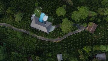 Vista aérea de una casa moderna con piscina, rodeada de un bosque denso.