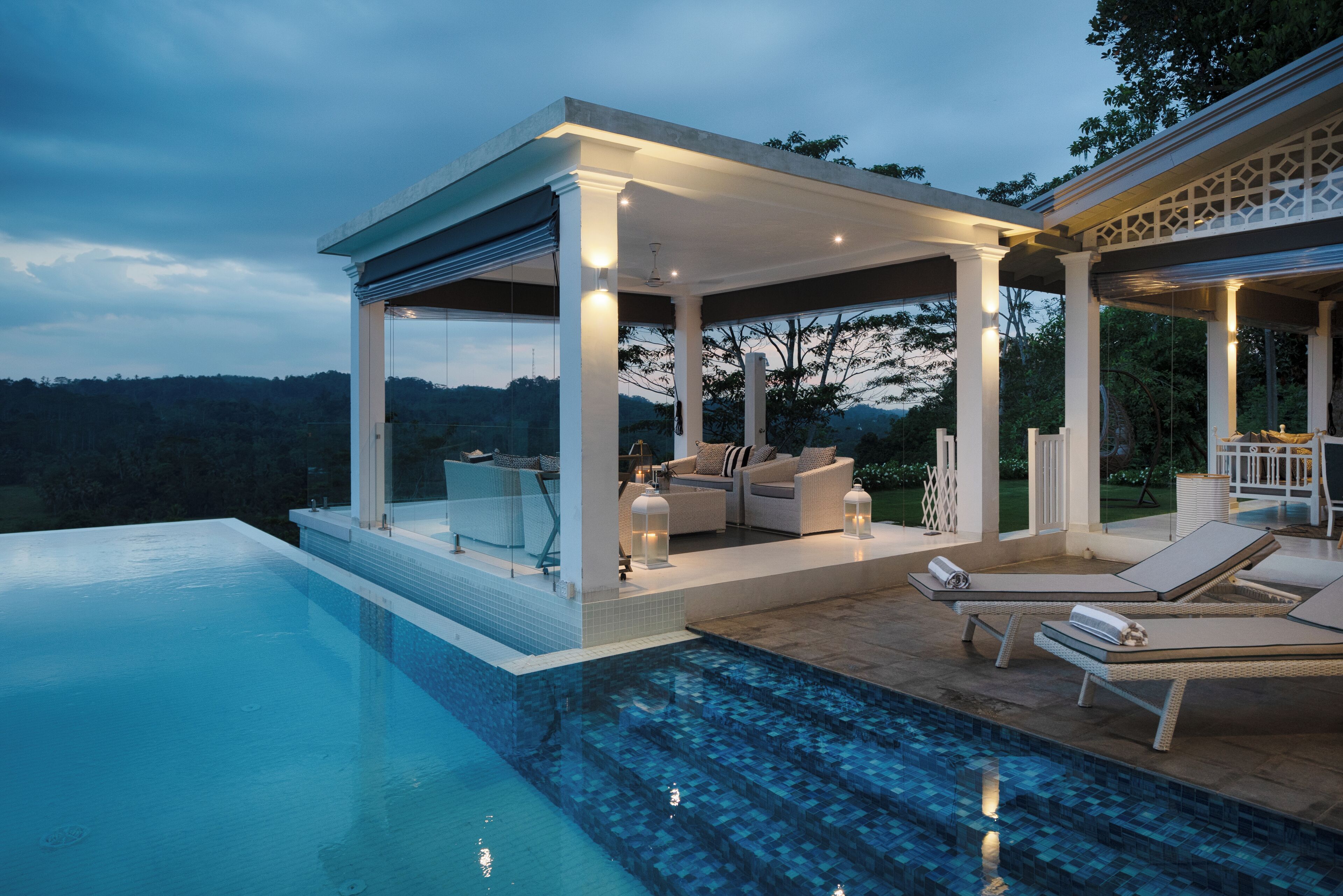 Un espace piscine extérieur moderne, doté de chaises longues et d’un coin salon abrité.