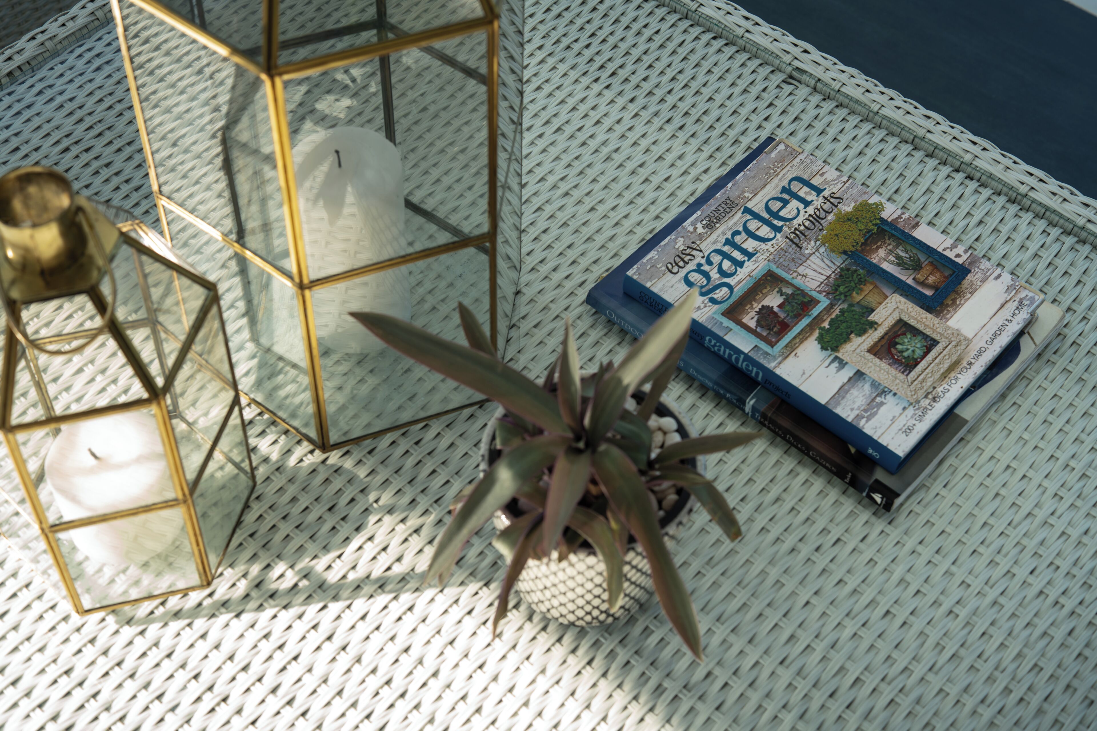 Een tijdschrift met de titel 'easy garden projects' op een geweven ondergrond, met een potplant en een kaars in een geometrische houder.