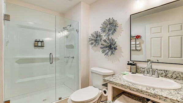 A modern bathroom with a glass shower enclosure, a white toilet, and a granite countertop sink. - Rancho El Charco Resort - Private Pool, Wildlife & Lake Retreat (La Joya)