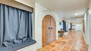 A hallway with a large wooden door, a window with curtains, and a tiled floor. - Rancho El Charco Resort - Private Pool, Wildlife & Lake Retreat (La Joya)