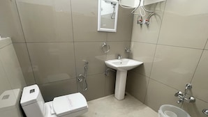 A bathroom with a toilet, sink, shower, and a trash bin. - The Eco Village Resort Srinagar (Srinagar)