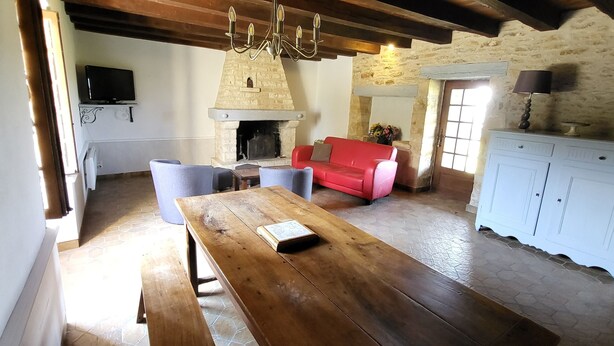 Ein rustikales Interieur mit einem Holztisch, einem roten Sofa, einem Steinkamin und einem weißen Schrank.