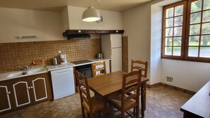 Eine kompakte Küche mit Essbereich, einem integrierten Geschirrspüler, einem Kühlschrank und einem Fenster mit Blick ins Grüne.