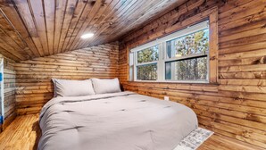Camera da letto in una baita di legno, con un letto, una finestra e una luce a soffitto.