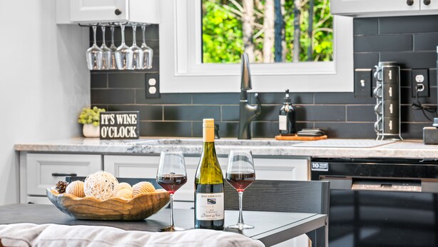 Una cucina moderna con una bottiglia di vino, due bicchieri e una ciotola di pane sul bancone.
