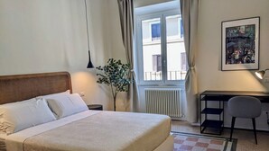 A neatly arranged bedroom with a bed, bedside table, lamp, and a desk with a chair. - Peaceful Roman Retreat (Roma)