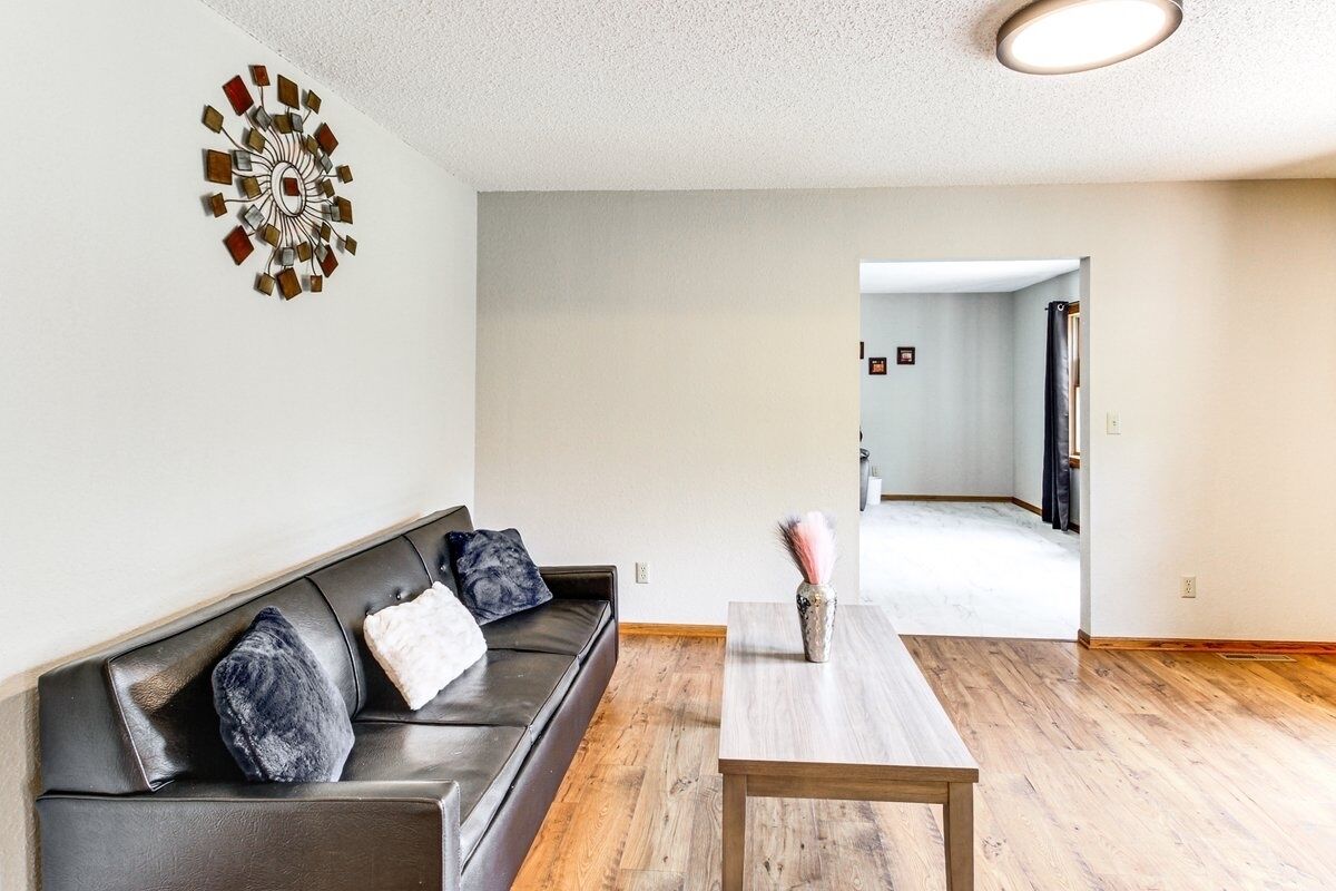 Un salon moderne avec un canapé en cuir foncé, une table basse en bois et un élément décoratif mural.