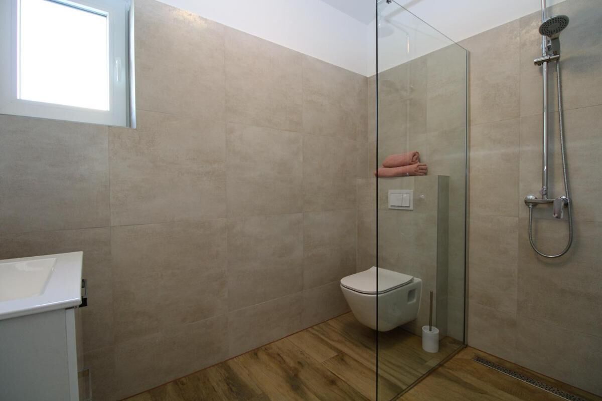 Een badkamer met een douchecabine van glas, een toilet en een wastafel.