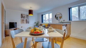 Een moderne keuken met een eethoek, grote ramen en een televisie in de hoek.