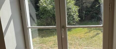 Une pièce dotée d’une grande fenêtre donnant sur un jardin.
