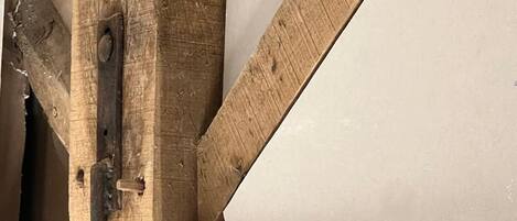 Een houten balkenconstructie met een metalen beugel en een wit paneel.