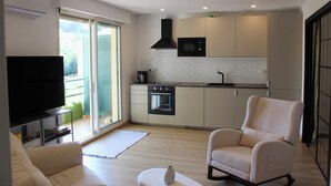 A modern kitchen with a microwave, oven, and sliding doors leading to a balcony. - Charming apartment near the sea (Cavalaire-sur-Mer)
