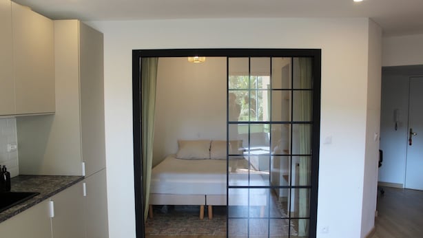 A modern kitchen with white cabinets and a black countertop. - Charming apartment near the sea (Cavalaire-sur-Mer)