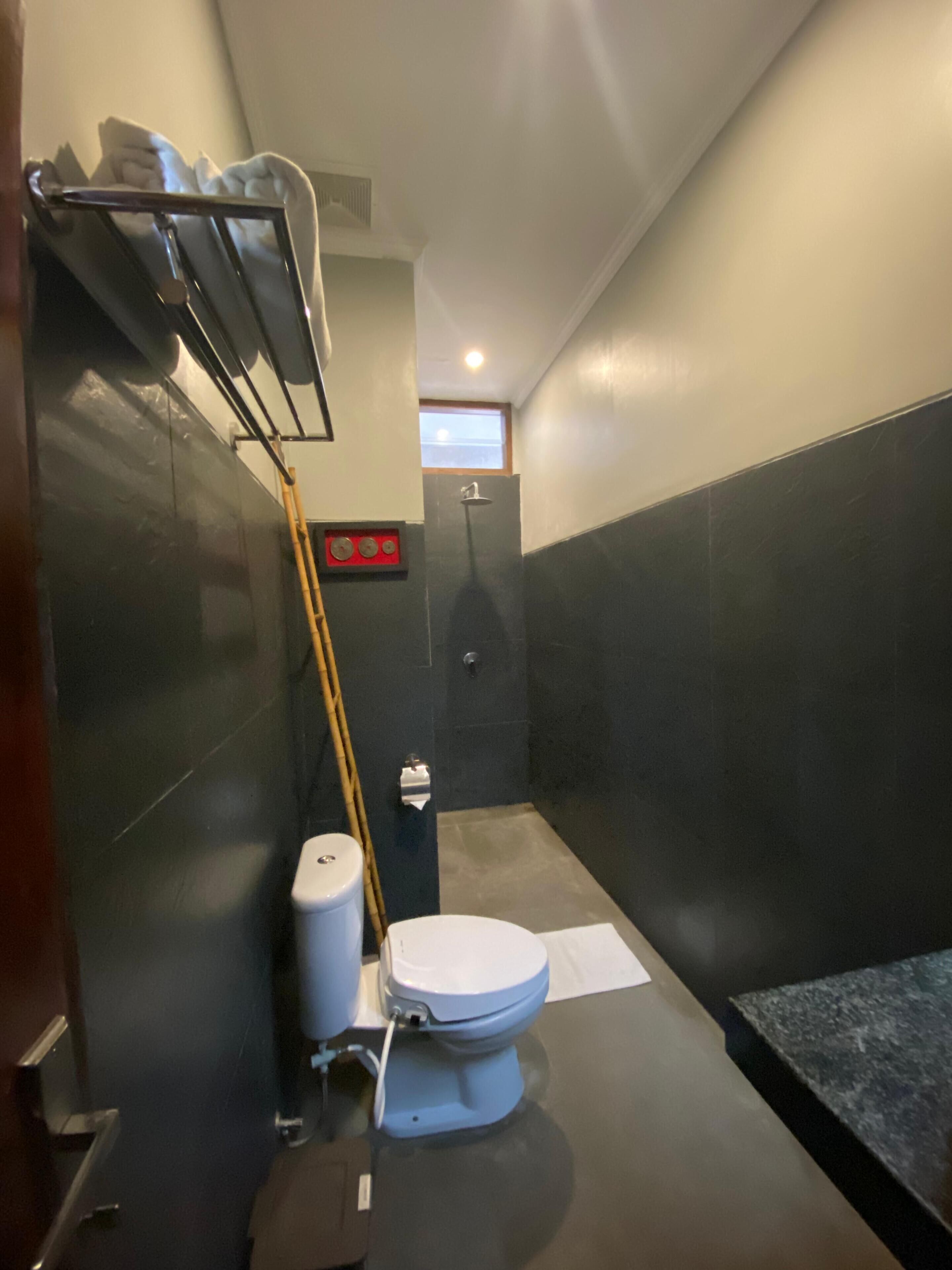 A compact bathroom with a toilet, a shower, and a hand dryer.
