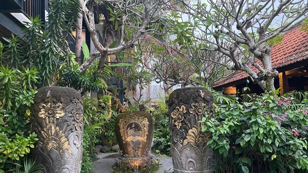A pathway flanked by intricately carved stone pillars leading to a building with a tiled roof. - The Belong Canggu Bali By. SDM (Canggu)