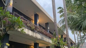 A multi-story hotel with balconies, palm trees, and a well-maintained garden. - The Belong Canggu Bali By. SDM (Canggu)