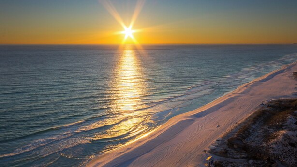 A beach with a sunset over the ocean, a sandy shoreline, and a distant landmass. - PlayaBella-Sandestin Escape|Lakefront|Golf Cart (Sandestin)