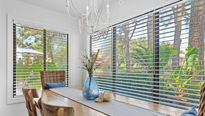 A dining area with a wooden table, wicker chairs, and a blue vase with greenery. - PlayaBella-Sandestin Escape|Lakefront|Golf Cart (Sandestin)