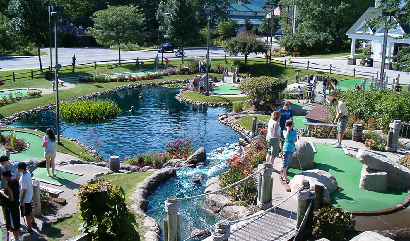 En minigolfbana med en damm, grönskande gångvägar och olika hinder.