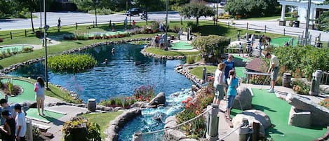 En minigolfbana med en damm, grönskande gångvägar och olika hinder.