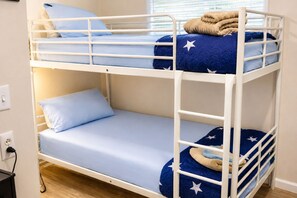 Un lit superposé à deux niveaux, chaque niveau étant équipé d’un matelas et de coussins bleus.