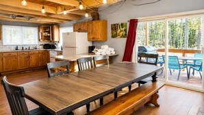 A spacious kitchen with wooden cabinets, a large dining table, and a view of the outdoors. - Cranmore Retreat, Walk to Slopes, Hot Tub, Game Room, Dog-Friendly, Sleeps 16+ (Conway)