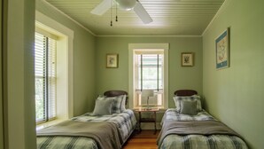 A room with two beds, a window, and a ceiling fan.