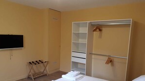 A hotel room with a bed, a wardrobe, a TV, and a shoe rack. - Gîte du Château de Montriou - up to 12 people (Feneu)