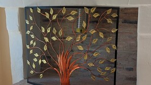 A fireplace with a decorative metal tree design. - Gîte du Château de Montriou - up to 12 people (Feneu)