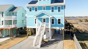 A two-story house with a balcony, a staircase leading to the entrance, and a view of the surrounding landscape.