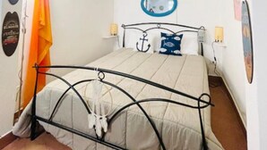 Une chambre à coucher avec un lit, une lampe suspendue, une étagère avec des objets décoratifs et une guitare accrochée au mur.