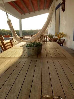 A wooden deck with a hammock, a potted plant, and a table with chairs. - Herdade do Vidigal (Montemor-o-Novo)