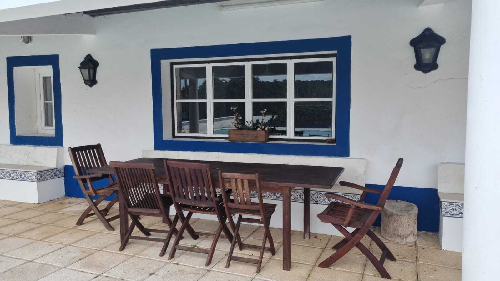 Un espace de restauration en plein air avec une table et des chaises, une fenêtre et un luminaire fixé au mur.