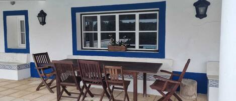Un espace de restauration en plein air avec une table et des chaises, une fenêtre et un luminaire fixé au mur.