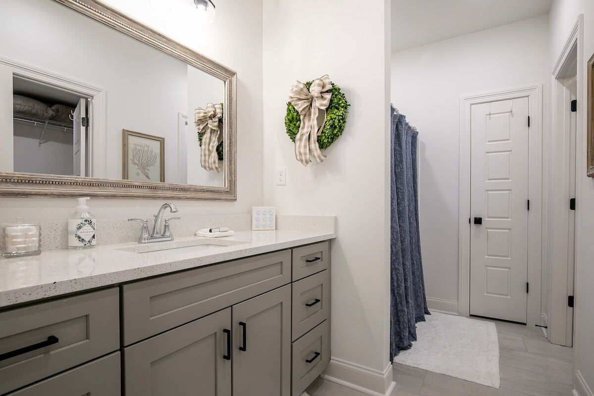 A bathroom with a white vanity, a large mirror, a towel rack, and a shower curtain.