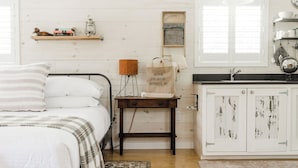 Un dormitorio acogedor con cama, mesita de noche y un pequeño estante de madera con libros y un farol.