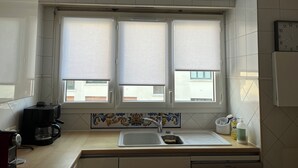 Eine Küche mit Spüle, Kaffeemaschine und einem Fenster mit Jalousien.