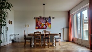 Ein Essbereich mit einem Holztisch und Stühlen, einer modernen Pendelleuchte und einem farbenfrohen, abstrakten Gemälde an der Wand.