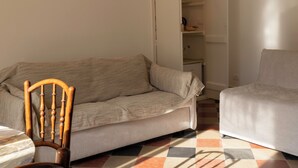 Un salon avec un canapé, une chaise en bois et un placard entrouvert.