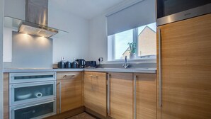 A modern kitchen with wooden cabinets, stainless steel appliances, and a window providing natural light. - Quaint 1 Bedroom 1st Floor Flat (Doncaster)