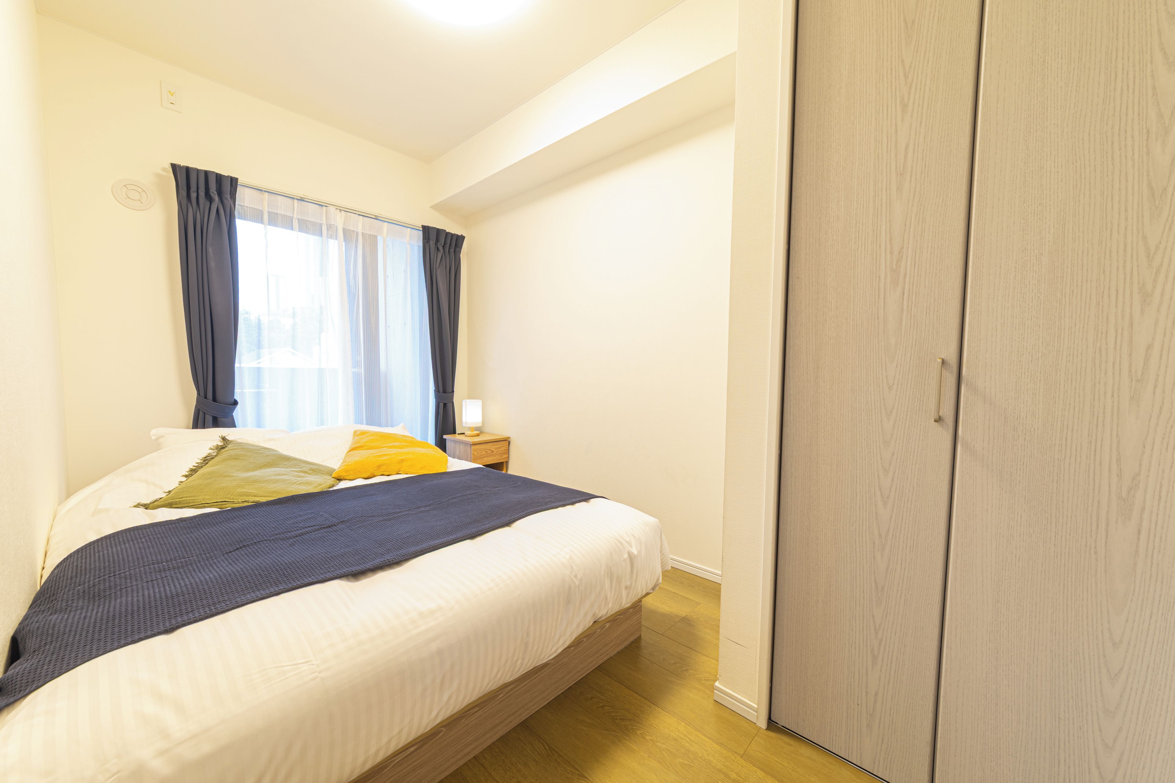 A bedroom with a bed, a nightstand, a lamp, and a wardrobe.