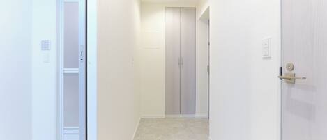 A narrow hallway with a wooden floor, white walls, and a closed door at the end.