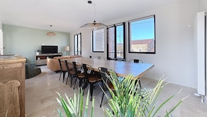 A modern kitchen with a large island, dining area, and large windows.
