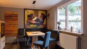 Un comedor con una mesa y sillas, un cuadro grande en la pared y una ventana con vistas al exterior.