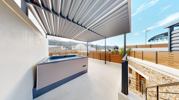 A rooftop terrace with a built-in hot tub, a view of the cityscape, and a stone wall.