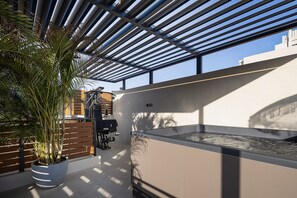 A modern outdoor area with a pergola, exercise equipment, and a large planter with a palm tree.