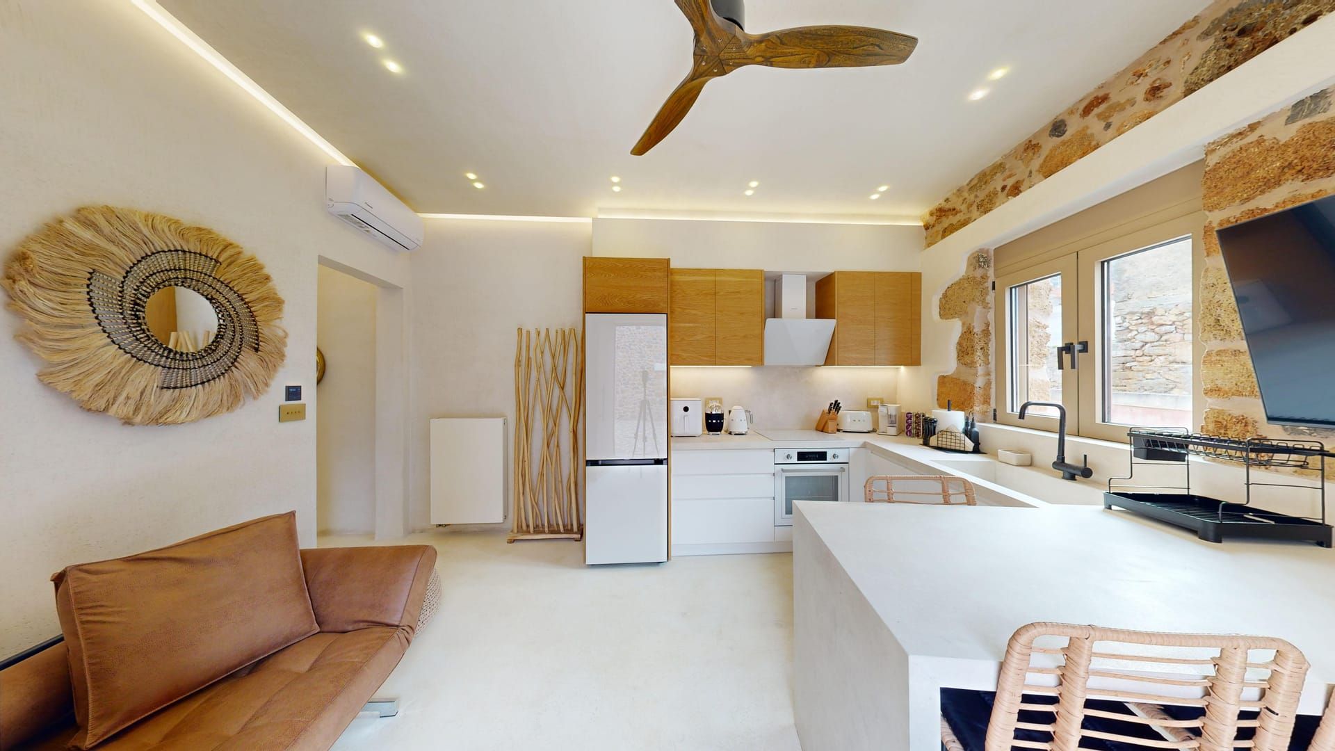 A modern kitchen with a central island, wooden cabinets, and a ceiling fan.