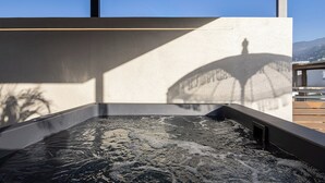 Ett modernt spaområde med ett bubbelbad, klar himmel och utsikt över stadsbilden.