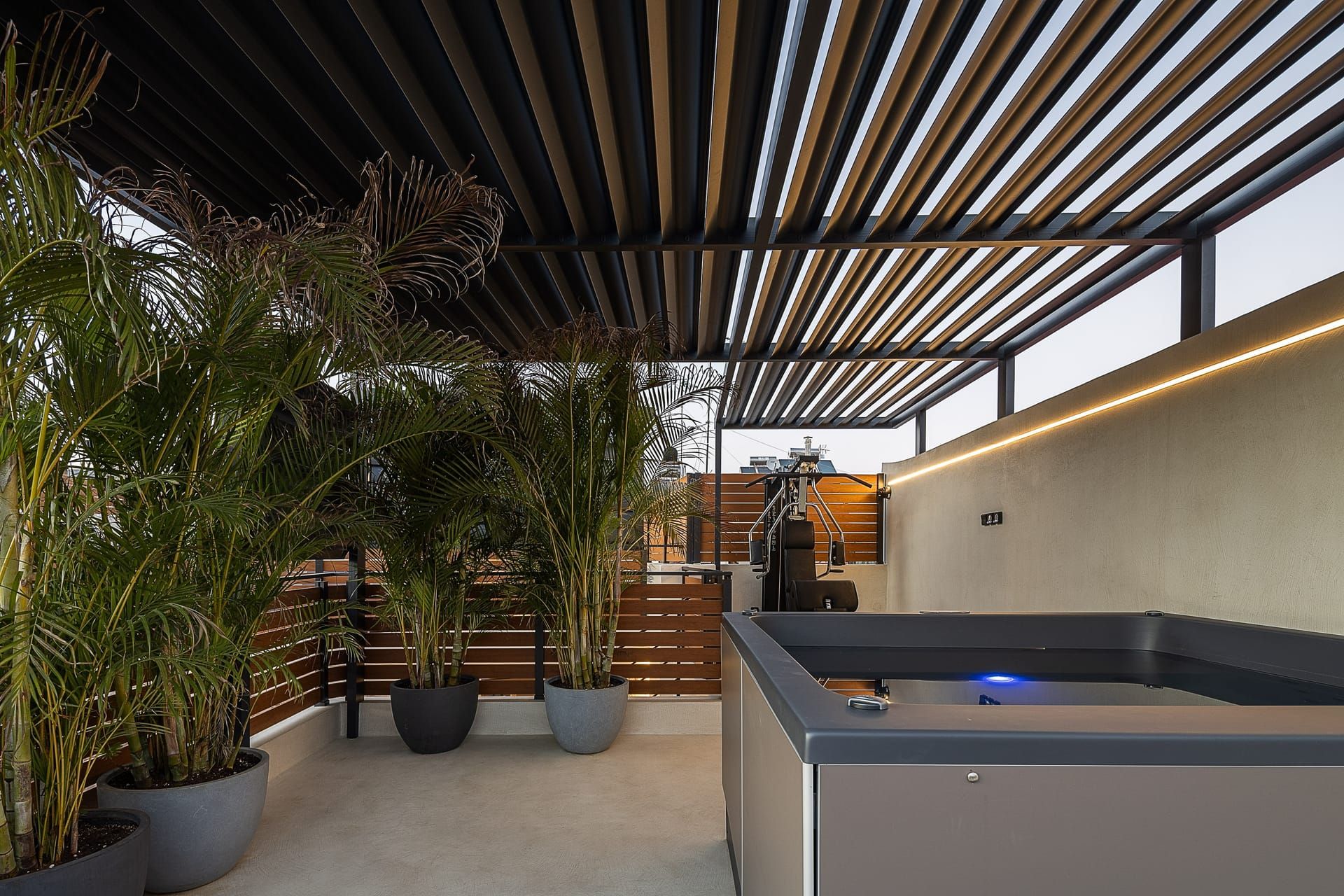 A modern outdoor area with a pool, potted plants, and a wooden slatted ceiling.
